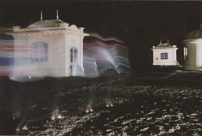 白い建物に色とりどりの光のレイヤーが通りぬける