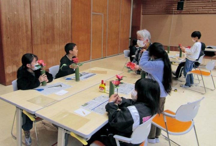 和紙で赤い椿の花を作る子供たち