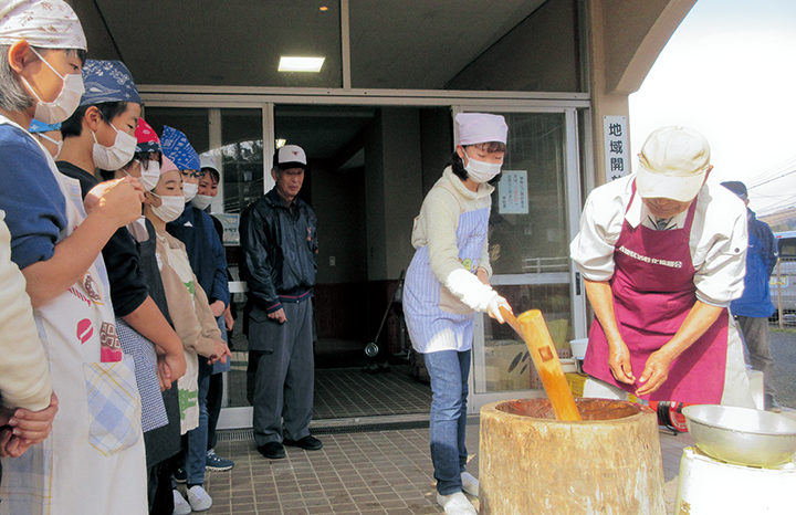 国府東小学校5年生が地域ボランティアと餅つきをしている様子