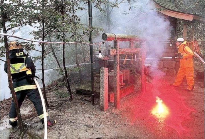 鳥居の近くから放水する消防団