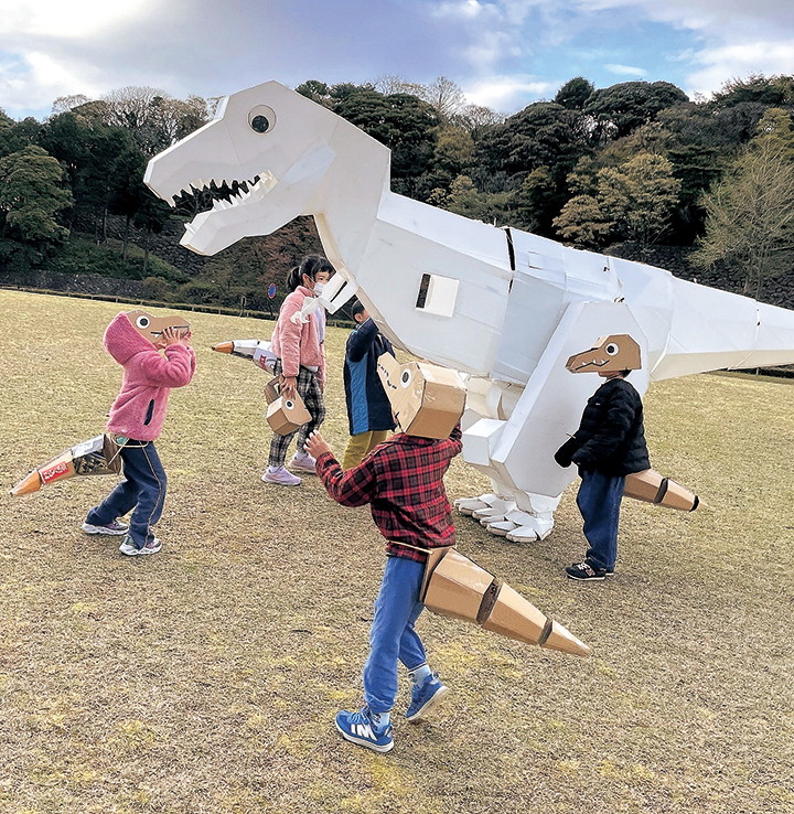 白いティラノサウルス「うちのシロ」と一緒に散歩をするティラノサウルスに扮した子どもたち